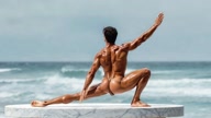 Parivrtta Trikonasana. Revolved-Triangle-Pose. Yogi. Greek athlete, sweaty muscle yoga on wet marble 1m0s
